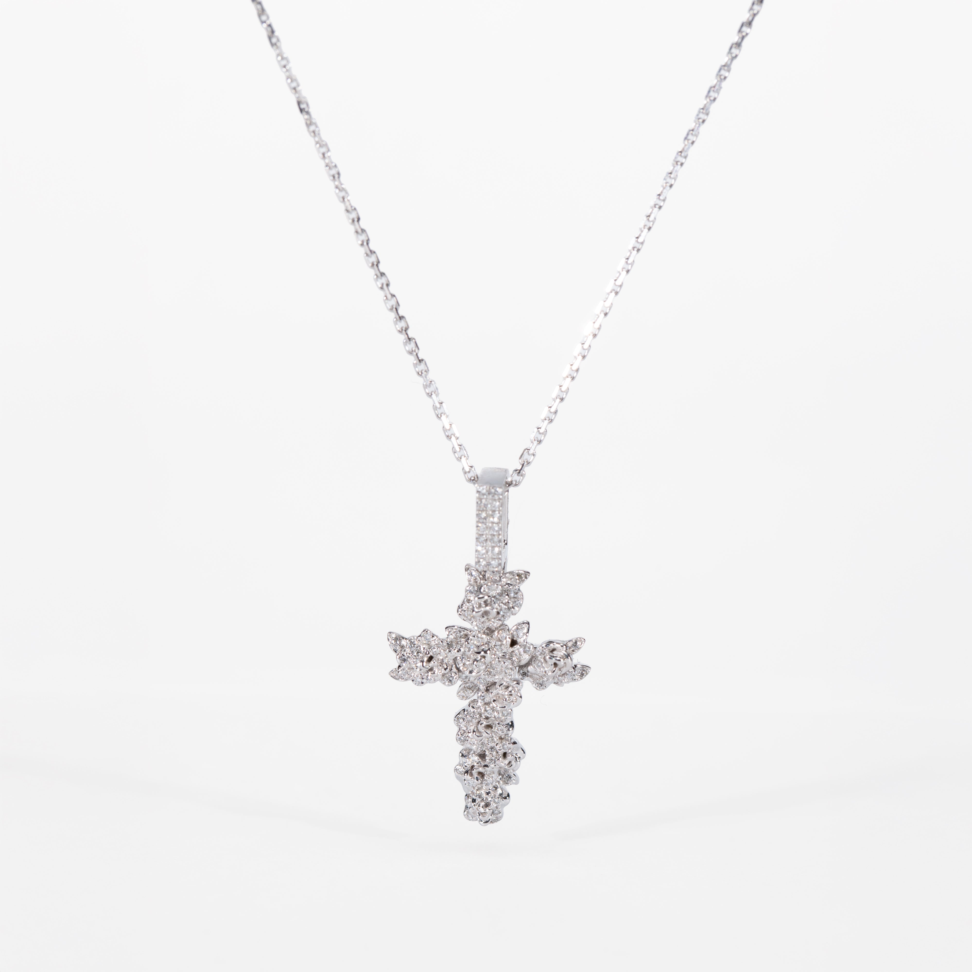white gold cross pendant necklace on a white background