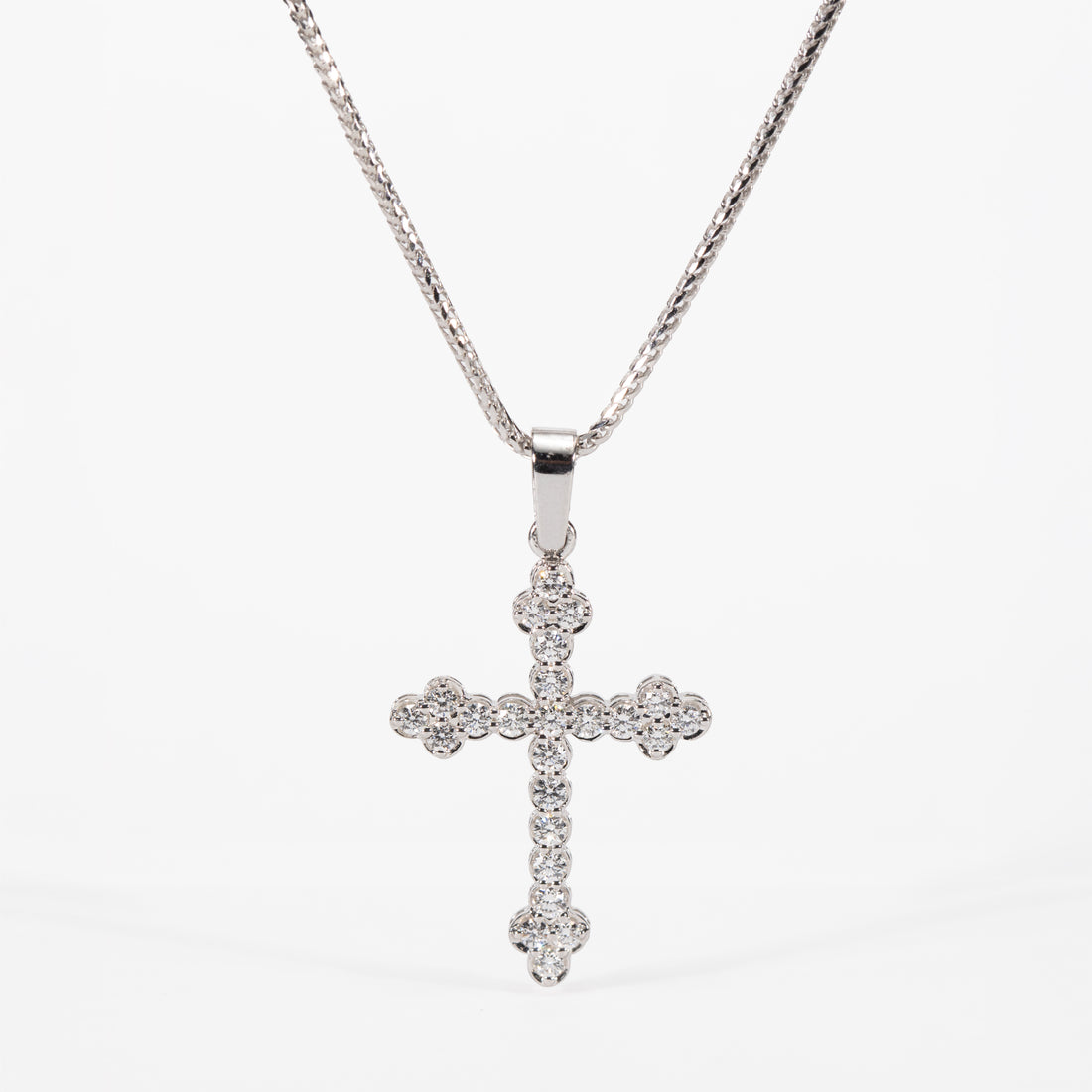 Silver cross pendant necklace on a white background