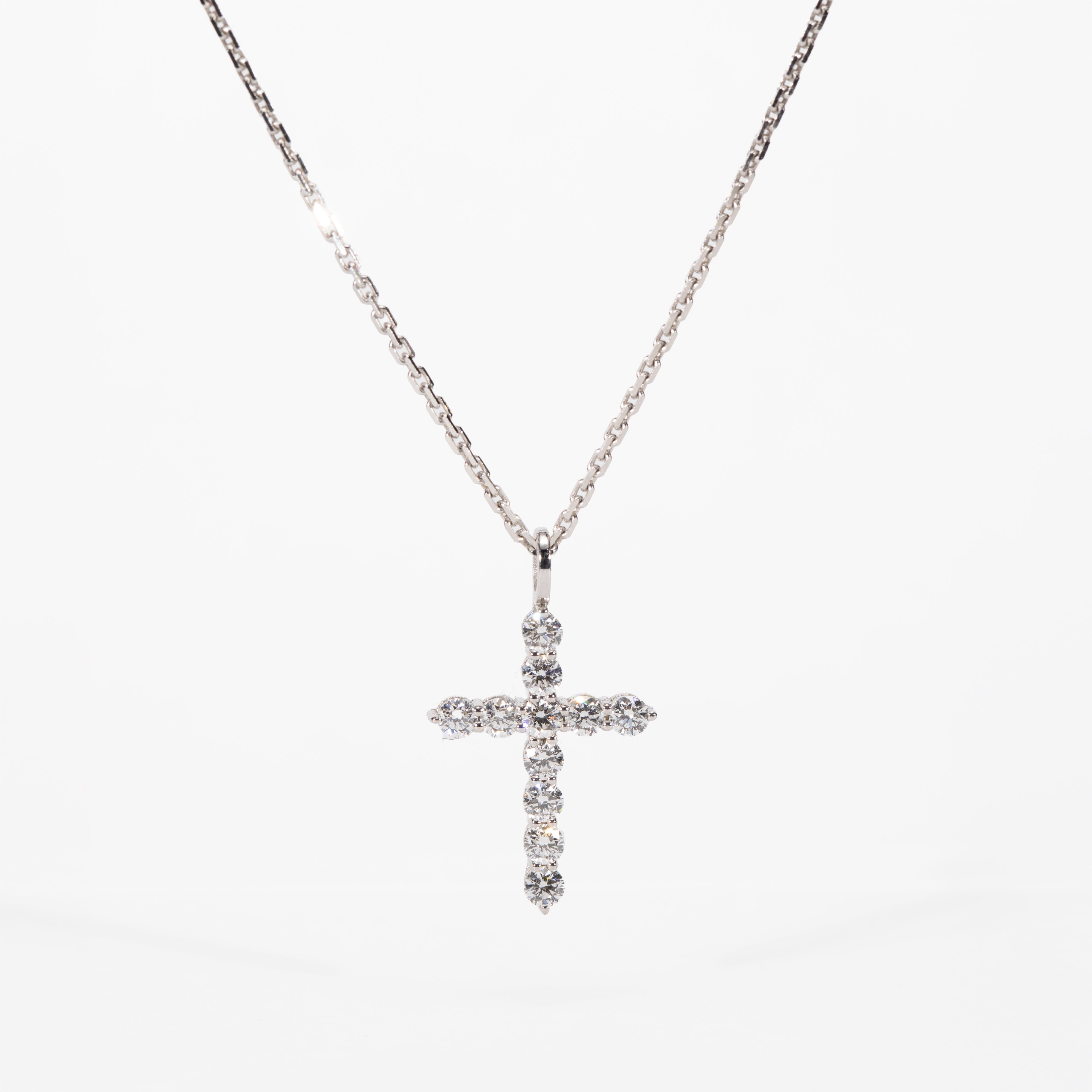 white gold cross necklace with clear stones on a white background