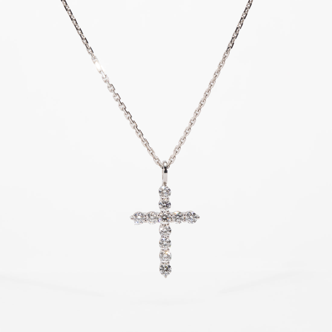 white gold cross necklace with clear stones on a white background